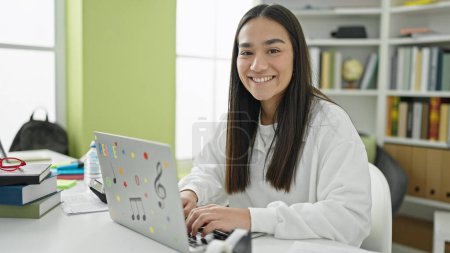 Téléchargez les photos : Jeune belle étudiante hispanique utilisant un ordinateur portable étudier à l'université salle de classe - en image libre de droit