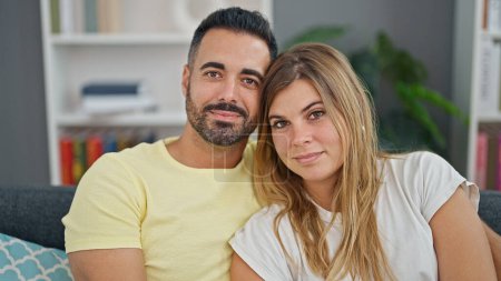 Photo for Man and woman couple hugging each other sitting on sofa at home - Royalty Free Image