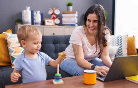 Foto de Madre e hijo usando portátil jugando en casa - Imagen libre de derechos