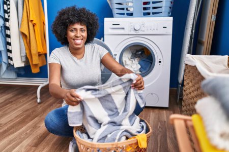 Téléchargez les photos : African american woman smiling confident washing clothes at laundry room - en image libre de droit