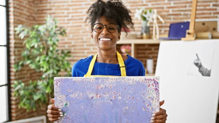 Foto de African american woman artist smiling confident holding draw at art studio - Imagen libre de derechos