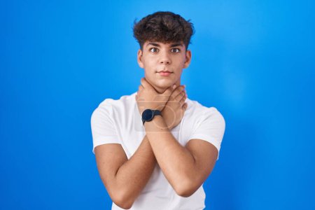 Photo for Hispanic teenager standing over blue background shouting suffocate because painful strangle. health problem. asphyxiate and suicide concept. - Royalty Free Image