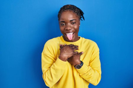 Photo for Beautiful black woman standing over blue background sticking tongue out happy with funny expression. emotion concept. - Royalty Free Image