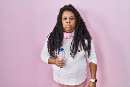 Photo for Plus size hispanic woman wearing sportswear and headphones looking sleepy and tired, exhausted for fatigue and hangover, lazy eyes in the morning. - Royalty Free Image