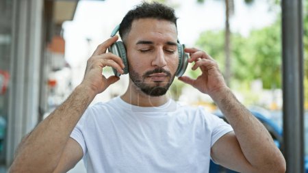 Foto de Hombre árabe joven escuchando música en la calle - Imagen libre de derechos