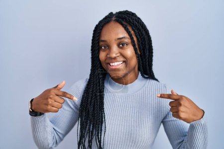 Photo for African american woman standing over blue background looking confident with smile on face, pointing oneself with fingers proud and happy. - Royalty Free Image