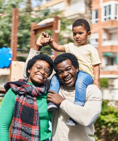 Téléchargez les photos : Famille afro-américaine tenant garçon sur les épaules à l'aire de jeux - en image libre de droit