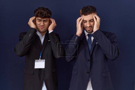 Photo for Two hispanic business men wearing business clothes with hand on head for pain in head because stress. suffering migraine. - Royalty Free Image