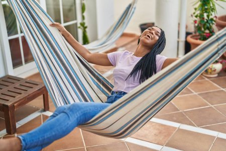 Photo for African american woman smiling confident swinging on hammock at home terrace - Royalty Free Image