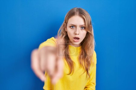 Photo for Young caucasian woman standing over blue background pointing displeased and frustrated to the camera, angry and furious with you - Royalty Free Image