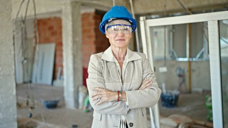 Photo for Middle age blonde woman architect smiling confident standing with arms crossed gesture at construction site - Royalty Free Image
