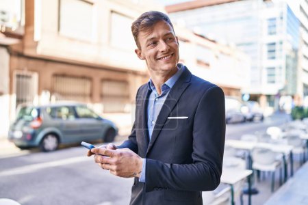 Foto de Trabajador de negocios joven sonriendo confiado usando teléfono inteligente en la calle - Imagen libre de derechos