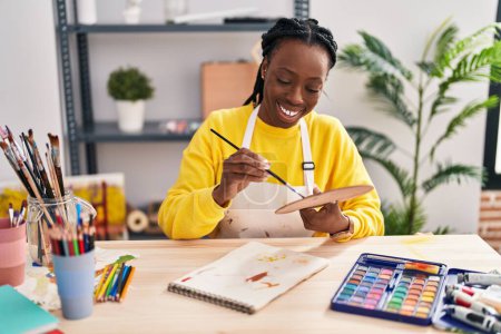 Téléchargez les photos : Femme artiste afro-américaine souriant dessin confiant sur ordinateur portable au studio d'art - en image libre de droit