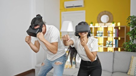 Foto de Hombre y mujer pareja usando gafas de realidad virtual boxeo en casa - Imagen libre de derechos