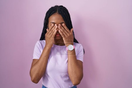 Téléchargez les photos : Femme afro-américaine avec des tresses debout sur fond rose frottant les yeux pour la fatigue et les maux de tête, somnolent et l'expression fatiguée. problème de vision - en image libre de droit