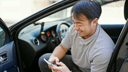 Foto de Usando el teléfono inteligente sentado en el coche en la calle - Imagen libre de derechos