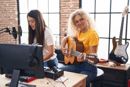 Foto de Dos mujeres músicos cantando canciones tocando guitarra clásica y piano en el estudio de música - Imagen libre de derechos