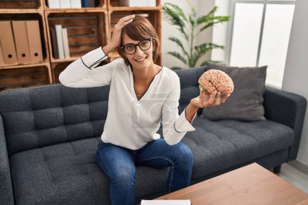 Photo for Brunette woman working at therapy office holding brain stressed and frustrated with hand on head, surprised and angry face - Royalty Free Image