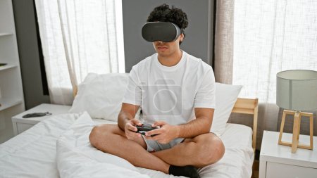 Photo for Young latin man playing video game using virtual reality glasses and joystick at bedroom - Royalty Free Image