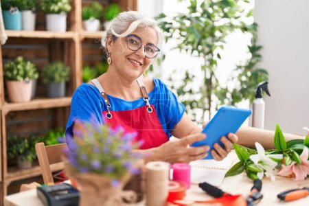 Photo for Middle age grey-haired woman florist smiling confident using touchpad at florist - Royalty Free Image