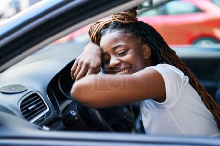 Foto de Mujer afroamericana sonriendo confiada apoyada en el volante en la calle - Imagen libre de derechos