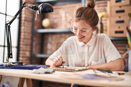 Téléchargez les photos : Jeune femme blonde souriant dessin confiant sur ordinateur portable au studio d'art - en image libre de droit