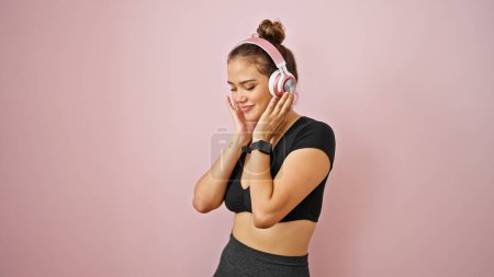 Photo for Young beautiful hispanic woman wearing sportswear listening to music over isolated pink background - Royalty Free Image