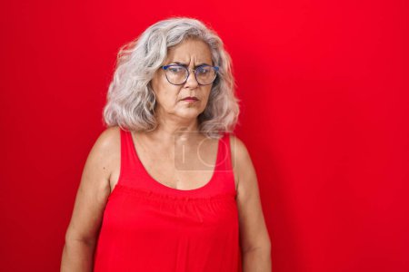 Photo for Middle age woman with grey hair standing over red background skeptic and nervous, frowning upset because of problem. negative person. - Royalty Free Image