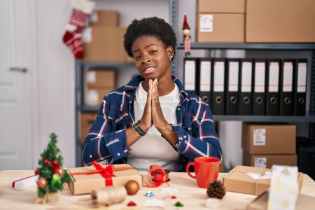 Photo for African american woman working at small business doing christmas decoration begging and praying with hands together with hope expression on face very emotional and worried. begging. - Royalty Free Image