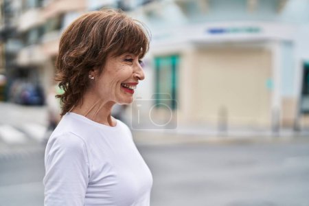 Foto de Mujer de mediana edad sonriendo confiado mirando a un lado en la calle - Imagen libre de derechos