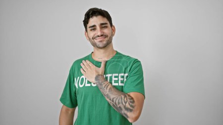 Téléchargez les photos : Jeune homme hispanique volontaire souriant confiant poitrine touchante sur fond blanc isolé - en image libre de droit