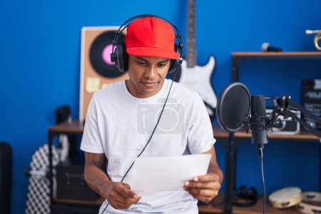 Téléchargez les photos : Jeune homme latin artiste chantant chanson lecture partition au studio de musique - en image libre de droit