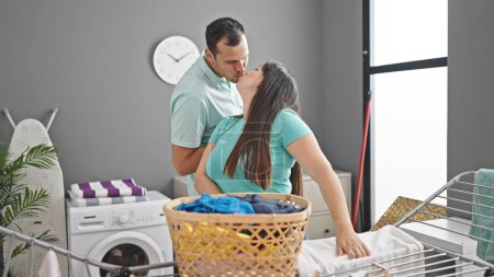 Foto de Pareja hispana besando ropa colgada en tendedero en la lavandería - Imagen libre de derechos