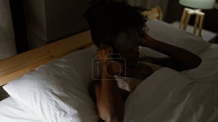 Photo for African american woman wearing sleep mask to sleep at bedroom - Royalty Free Image