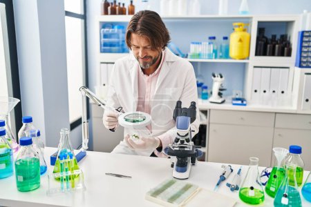 Téléchargez les photos : Homme du Moyen Age scientifique à la recherche d'une plante avec loupe au laboratoire - en image libre de droit