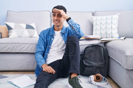 Photo for Young hispanic man sitting on the floor studying for university very happy and smiling looking far away with hand over head. searching concept. - Royalty Free Image