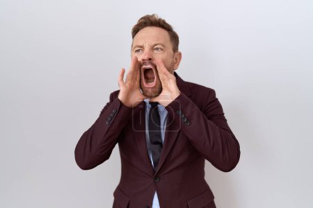 Photo for Middle age business man with beard wearing suit and tie shouting angry out loud with hands over mouth - Royalty Free Image