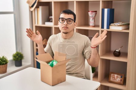 Photo for Young arab man with open gift in cardboard box shouting and screaming loud to side with hand on mouth. communication concept. - Royalty Free Image