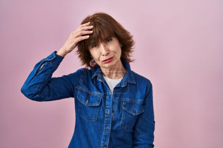 Photo for Middle age woman standing over pink background worried and stressed about a problem with hand on forehead, nervous and anxious for crisis - Royalty Free Image