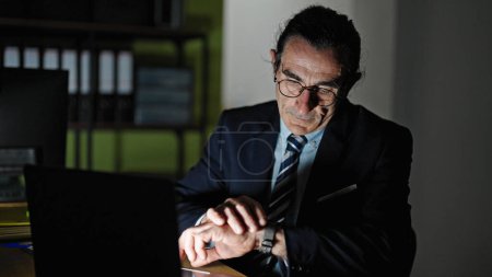 Téléchargez les photos : Homme d'âge moyen travailleur d'affaires en utilisant un ordinateur portable regarder au bureau - en image libre de droit
