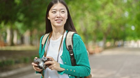 Foto de Joven turista china con mochila sonriendo en el parque - Imagen libre de derechos