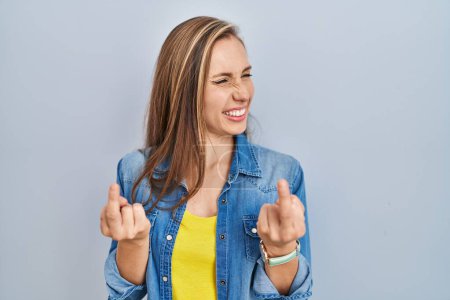 Foto de Young blonde woman standing over blue background showing middle finger doing fuck you bad expression, provocation and rude attitude. screaming excited - Imagen libre de derechos