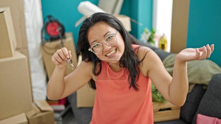 Foto de Joven mujer china sonriendo confiada sosteniendo nuevas llaves de la casa en un nuevo hogar - Imagen libre de derechos