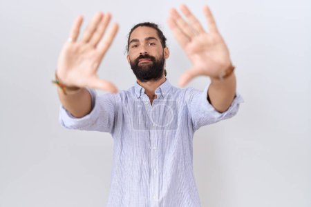 Téléchargez les photos : Homme hispanique avec barbe portant une chemise décontractée faisant cadre en utilisant les mains, les paumes et les doigts, perspective de la caméra - en image libre de droit