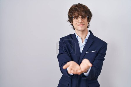 Foto de Joven empresario hispano con gafas sonriendo con las palmas de las manos juntas recibiendo o dando gesto. retención y protección - Imagen libre de derechos