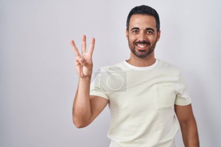 Photo for Hispanic man with beard standing over isolated background showing and pointing up with fingers number three while smiling confident and happy. - Royalty Free Image