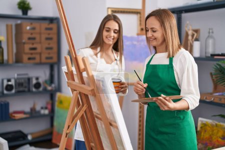 Photo for Two women artists smiling confident drinking coffee drawing at art studio - Royalty Free Image