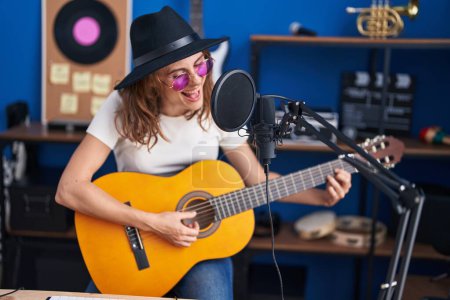 Photo for Young woman musician singing song playing classical guitar at music studio - Royalty Free Image
