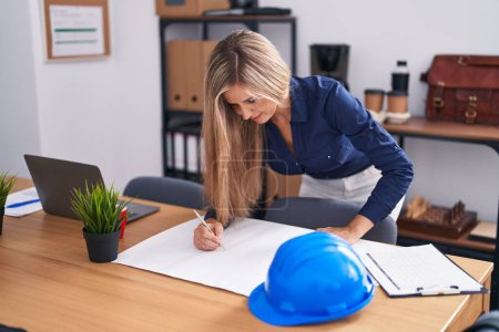 Photo for Young blonde woman architect drawing house plans at office - Royalty Free Image