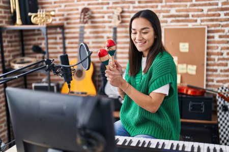 Téléchargez les photos : Jeune musicienne hispanique jouant des maracas au studio de musique - en image libre de droit
